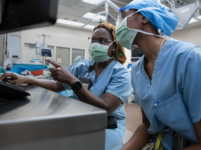 Two people working in a lab wearing masks and scrubs