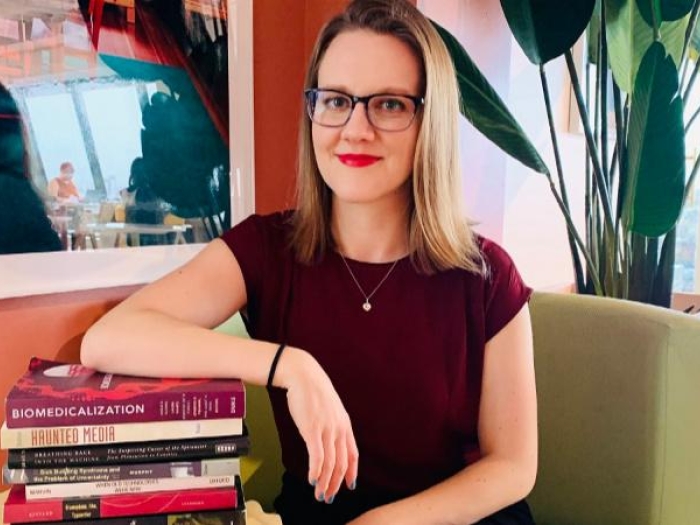 A woman sitting with a stack of books