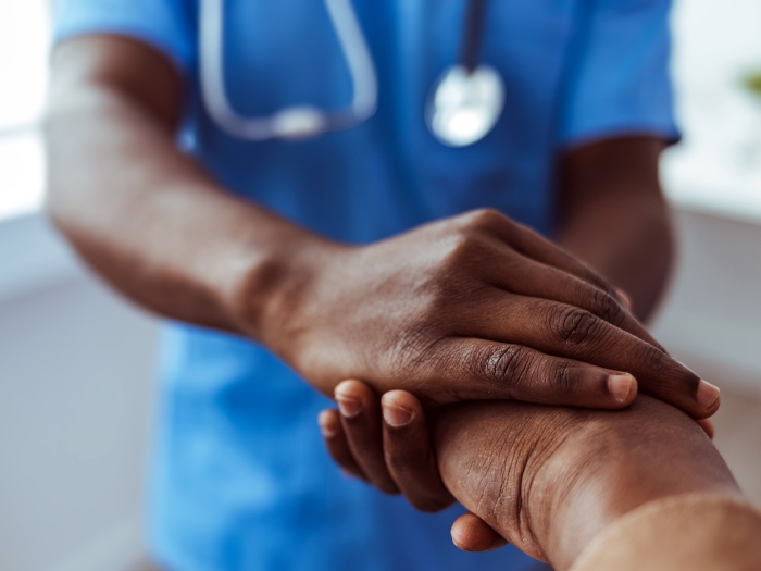 Health care provider with stethoscope holds patient's hand