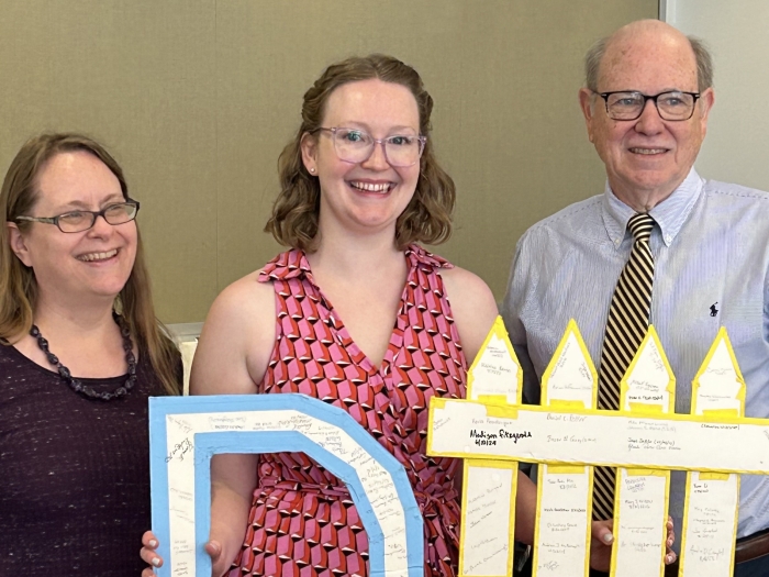 Madison Fitzgerald, Ph.D., after her defense, holding the department's D# sign. Every M&I grad student signs it after defending. Left to right: Melanie Pearson, Madison Fitzgerald and Harry Mobley