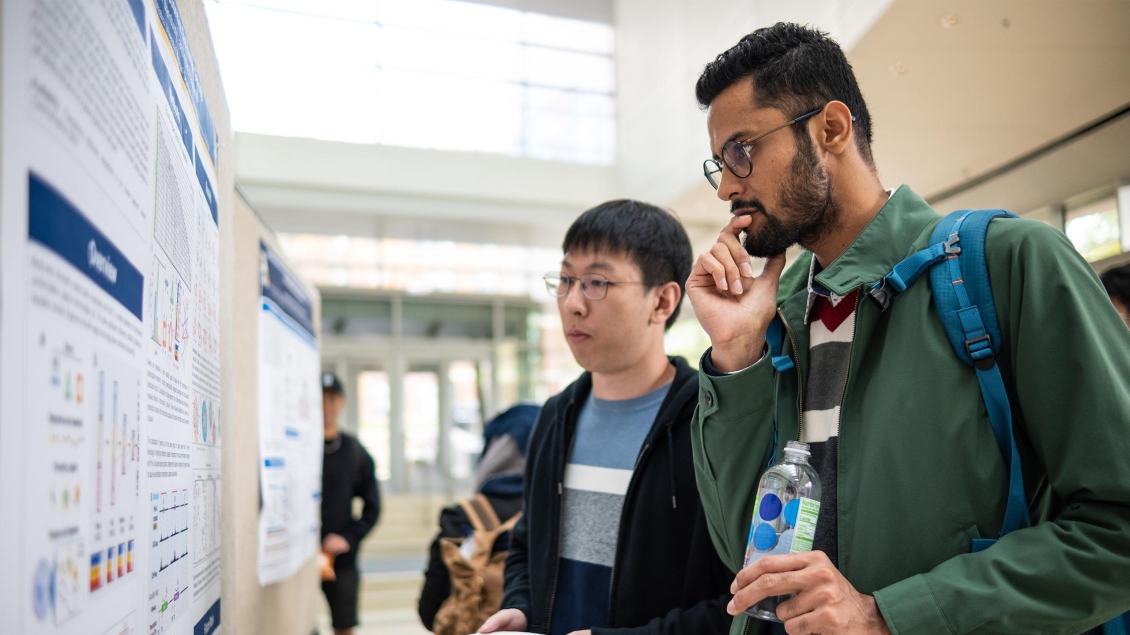  two students gather to read a poster