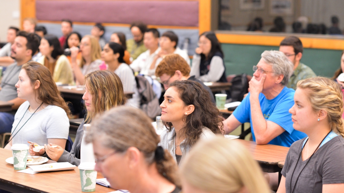 biochemistry students sit at tables and listen at a conference