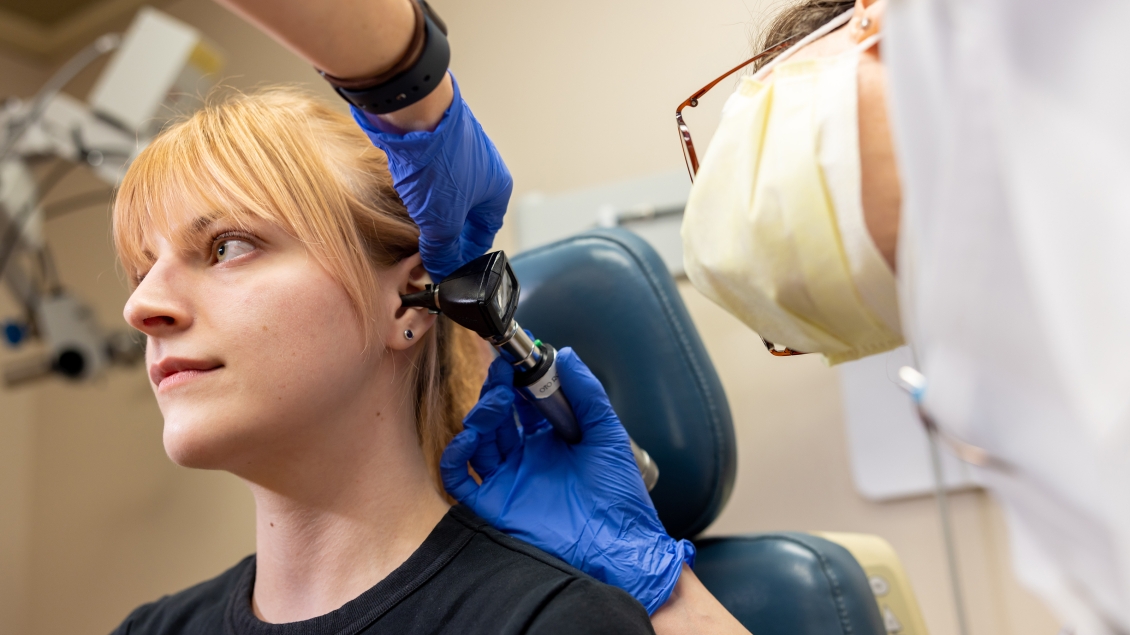 A patient gets her ear examined by a doctor