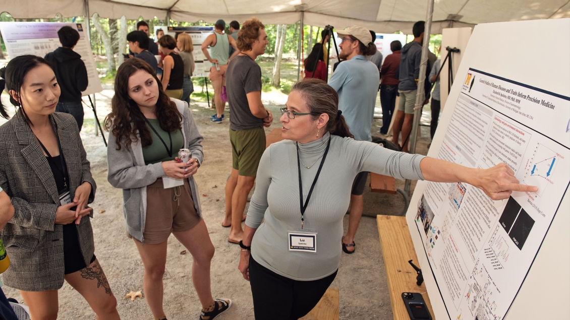 A group of people at a retreat under a tent reading a poster