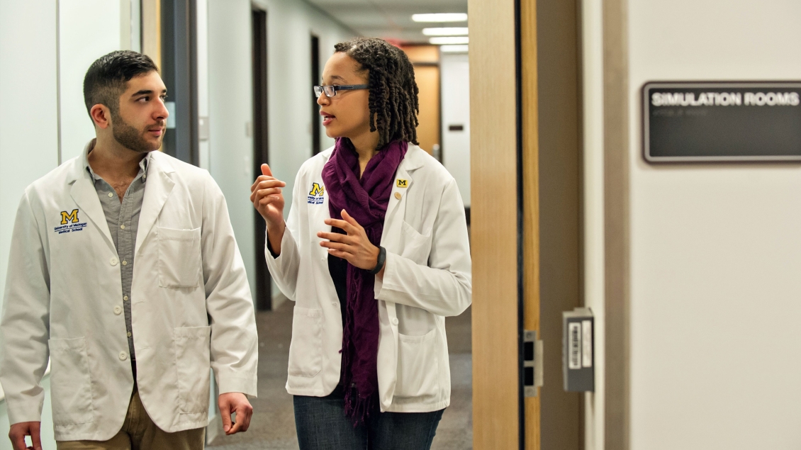 Two people walking in a hallway talking