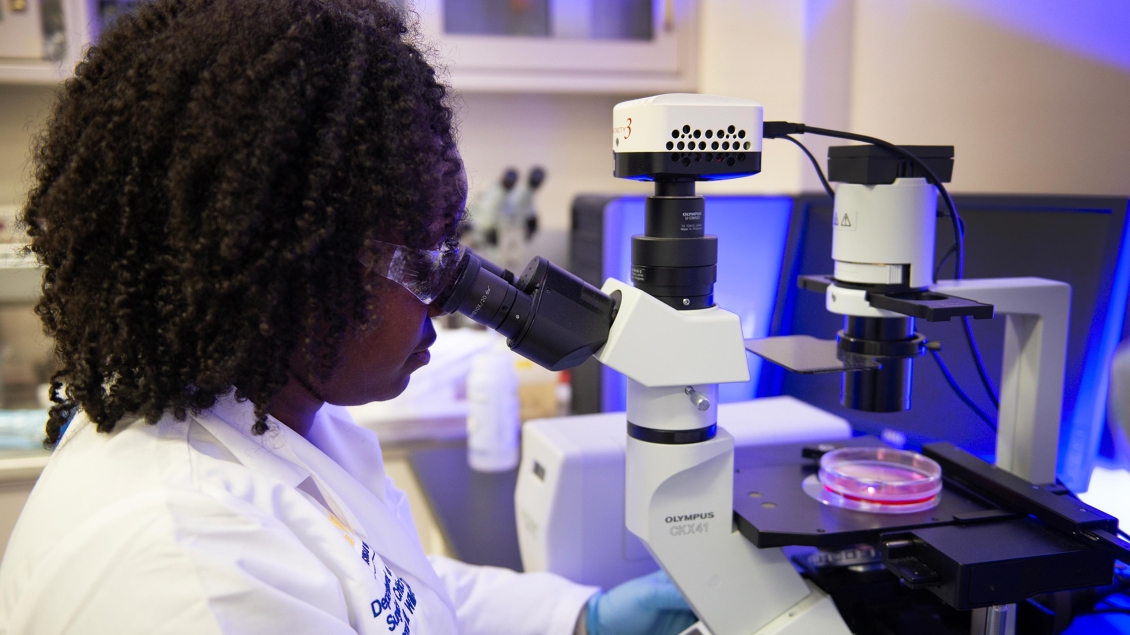 woman in laboratory looking through a microscope 