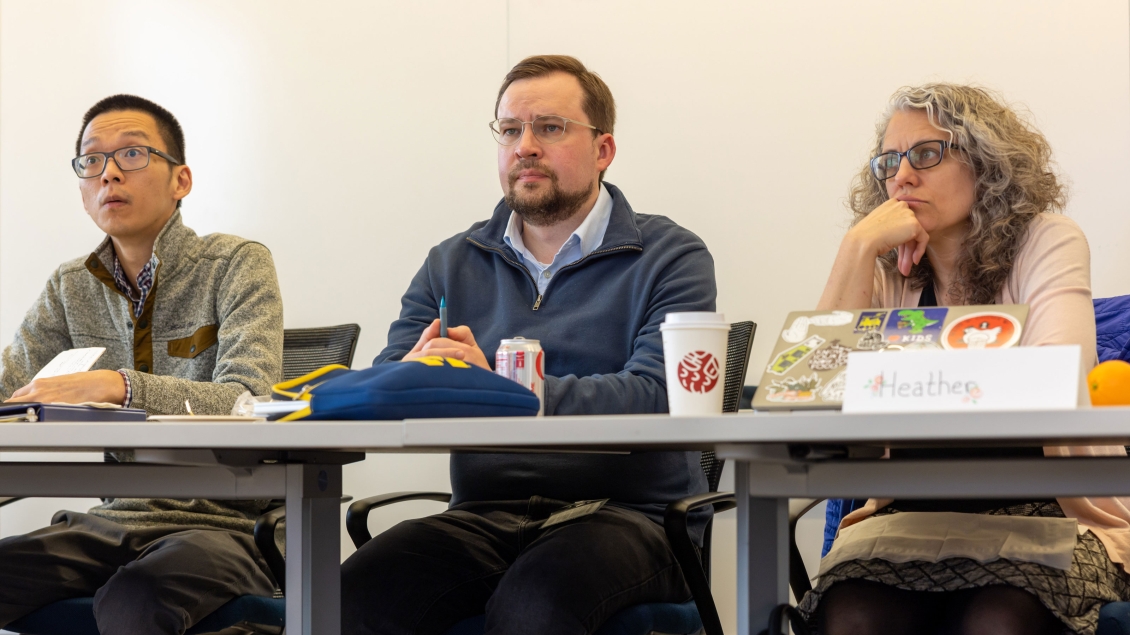 three people listening to a presentation