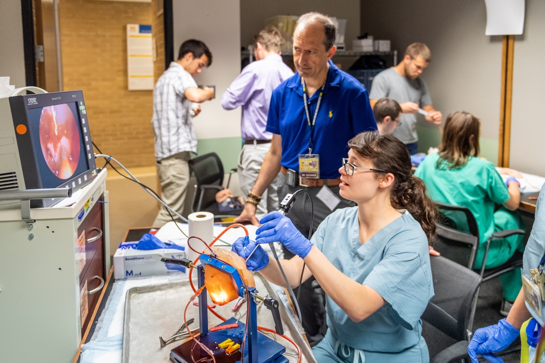 An otolaryngology student practices on a machine in the simulation lab